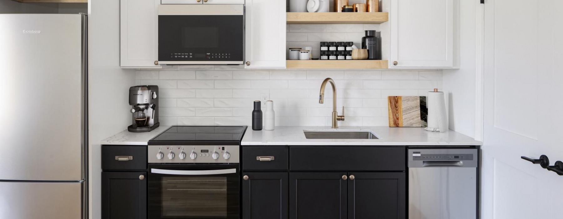 A modern kitchen featuring a sleek faucet and sink, a microwave built into the cabinets, and a coffee maker on the countertop. 